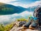 Backpack and hiking boots at the shore of beautiful scenic mountain lake