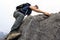 Backpacker climbing rock on mountain top cliff edge