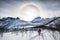 Backpacker climbing on snow peak with Sun halo on mountain range