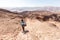 Backpacker descending hiking mountain ridge stone desert landscape