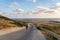 Backpacker hikes on the island of Cyprus, man with backpack walks along the highway on hill near Mediterranean Sea in