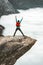 Backpacker Man jumping on Trolltunga rocky cliff edge