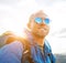 Backpacker man lifestyle portrait enjoying mountain landscape. He wears in blue rain coat poncho and blue sunglasses. Active