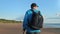 Backpacker mature man Scandinavian walking stick cardio sport training at sea beach forest landscape