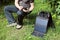 Backpacker is sitting on a camping chair and looking at smartphone that is charging from a solar panel