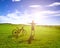 Backpacker standing next to bicycle with sunrise background