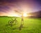 Backpacker standing next to bicycle with sunset background