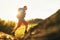 Backpacker traveler in trekking boots jumping over the ditch on mountain dirty path at summertime sunny day side shot image