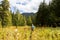 Backpacker walking high grass meadow.