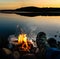 Backpacker warming his feet by a camp fire by the lake.