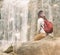 Backpacker woman looking at waterfall on sunny day.