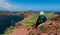 Backpacker woman sitting on a cliff