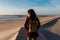 Backpacker young caucasian woman relaxing at the beach at sunset. walking by wooden passage or runway. Holidays and relaxation