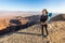 Backpacker young woman standing desert mountain edge canyon view