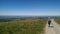 Backpaker woman walking on a dirt road, amazing view on french contryside.