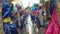 Backside of adult children in ornate coconut costume parades along the street, a festival to honor a patron saint