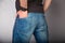 Backside cose up of a young fashion man in jeans with hand in pocket on gray background