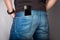 Backside cose up of a young fashion man in jeans with phone in pocket on gray background