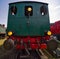 Backside of a dark green historic locomotive with large black buffers and yellow lights for identification purposes