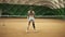 Backside footage of two athletic girls playing tennis in a covered tennis court. Woman in the frame with a leg