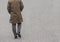 backside of a man who wearing a brown coat and walking on the road.