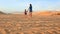 Backside Mother Small Girl Join Hands Walk on Dunes at Sunset