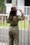 Backside portrait of an Indian young girl standing near a fence wearing garage mechanic attire and a cowboy hat. Indian lifestyle