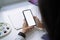 Backside view of artist woman hands using mockup white screen smart phone at desk