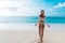 Backside view of girl with booty in beige colour bikini resting on deserted beach