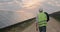 Backside view of male engineer in uniform walking at solar power plant. Man in hard helmet examining object and carrying