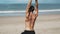 Backside view sporty man doing yoga exercises on sandy beach with ocean background