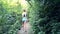 Backside view woman walks along track across jungle