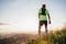 Backview of Active mountain trail runner dressed bright t-shirt with backpack enjoying the sunset while he sky running by