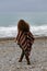 Backview portrait of happy brunette woman on the beach wearing p