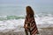 Backview portrait of happy brunette woman on the beach wearing p