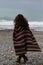 backview portrait of happy brunette woman on the beach wearing poncho