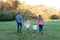 Backview of young family holding hands while walking at the park