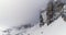 Backward aerial with snowy mountain,road and woods forest at Sella pass.Cloudy bad overcast foggy weather.Winter