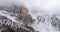 Backward aerial with snowy mountain and woods forest at Sella pass tilting down.Cloudy bad overcast foggy weather.Winter