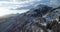 Backward aerial top view along road on white snow mountain in winter.Forest woods.Snowy mountains street path