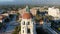 Backwards aerial footage of the bell tower at city hall with office buildings, shops and apartments in the city skyline