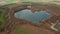 Backwards reveal surroundings of natural heart shaped lake in countryside. Aerial view of rural landscape. Germany