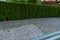 Backyard landscape design with footpaths of red tile and evergreen hedge of bush thuja