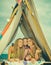 Backyard party. Camping vacation. Outdoor activity. Woman and child girl in tent. Wigwam.