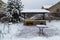 Backyard Patio.Landscape  with barbeque area, snowbanks of white snow, pine trees in country garden.