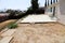 Backyard with patio slab and weeds and stucco house