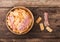 Bacon flavoured snacks chips in wooden bowl with grilled bacon rashers on wooden background. Top view