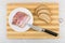 Bacon in plate, bread, kitchen knife on bamboo cutting board