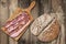 Bacon Rashers On Cutting Board And Dark Integral Wholegrain Bread Cut Loaf Set On Old Weathered Coarse Wood Grunge Background