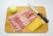 Bacon slices, Parmesan cheese, onion on the chopping Board. Carving knife